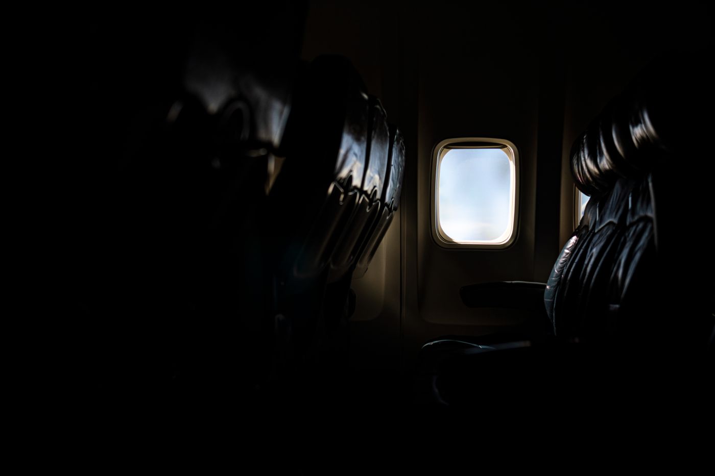 An illuminated window beside empty airplane seats