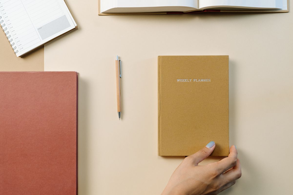 A weekly planner and notebook on a desk
